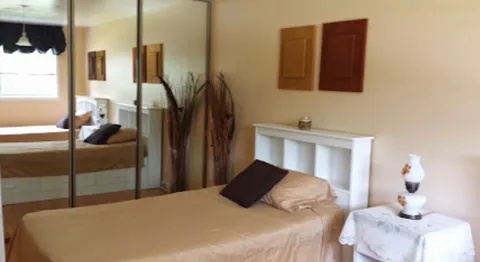 Bedroom with a single bed, mirrored wardrobe and small white nightstand