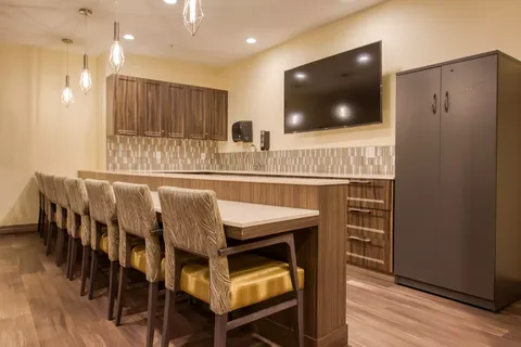 Counter with bar stools, wood cabinets and a blank television
