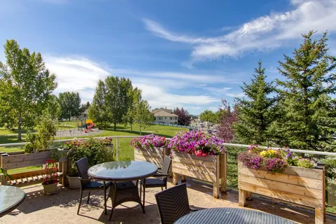 Patio with tables, chairs and flower planters overlooking a lawn