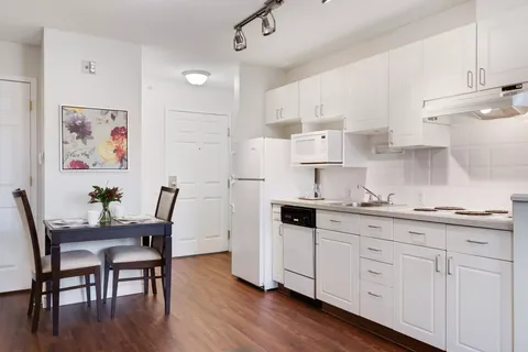 Kitchen with white cabinets, appliances and a small dining table