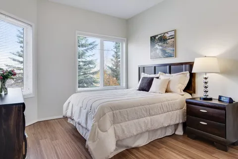 Bedroom with a double bed, bedside lamp and two windows