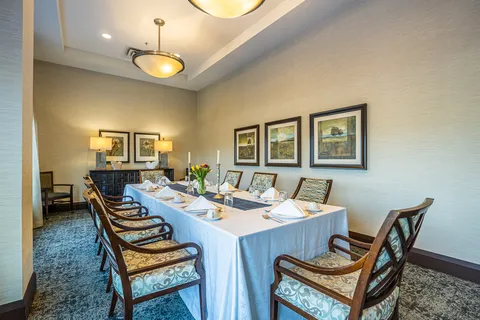 Private dining table with upholstered chairs and framed landscapes
