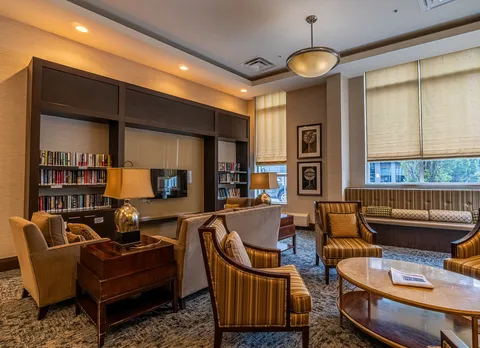 Armchairs and a sofa beside bookshelves and a television