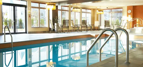 Indoor swimming pool with turquoise water, a metal railing and large windows