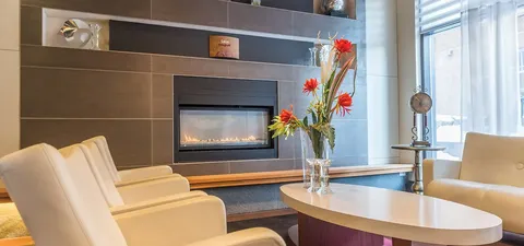 Cream armchairs around a table beside a fireplace