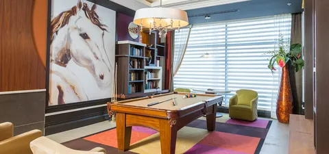 Billiards table beside bookshelves and a large painting of a horse