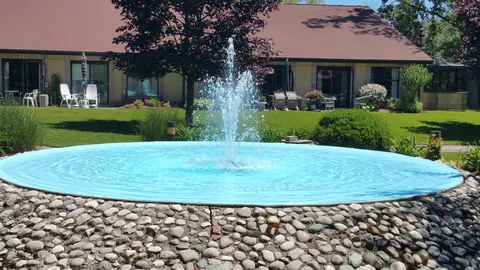 Circular fountain surrounded by stones beside the residence