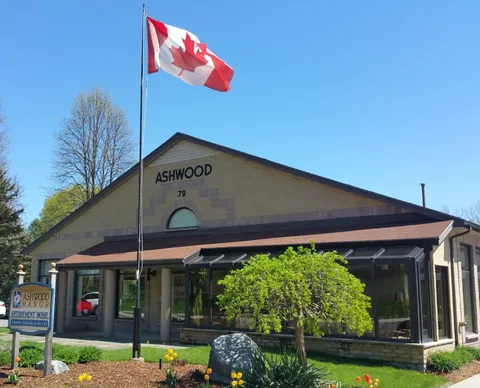 Residence entrance with a Canadian flag and planted flower beds
