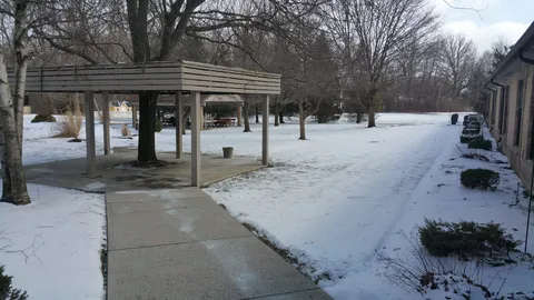 Snow-covered garden with a path and a wooden gazebo