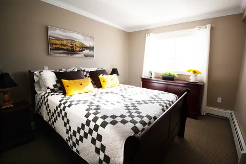 Bedroom with a patterned bedspread, bedside lamps and a window