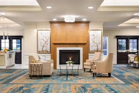 Lobby fireplace with armchairs, patterned carpet and reception doors.