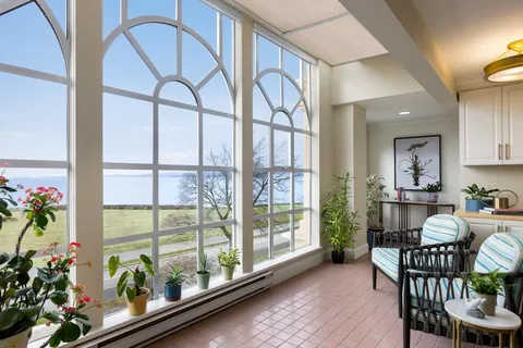 Sunroom with arched windows, seating and indoor plants.