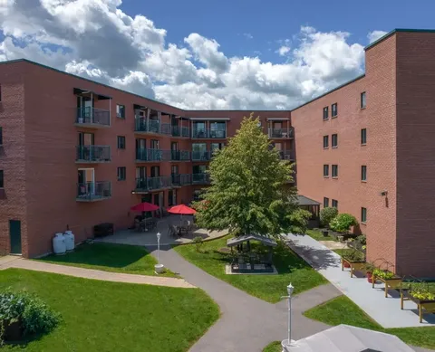 Brick residence buildings surrounding a courtyard with lawns, paths and seating