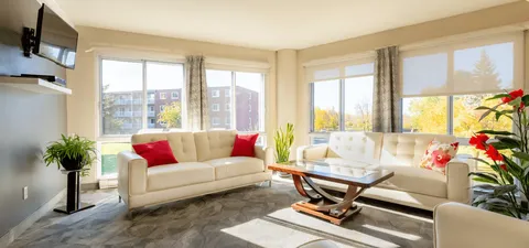 Bright sitting room with white sofas, plants and large windows