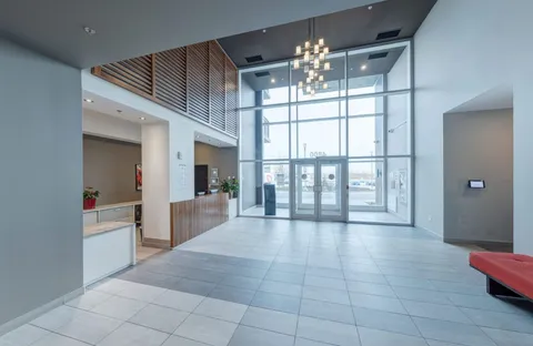 Bright tiled entrance lobby with tall glass doors and hanging lights