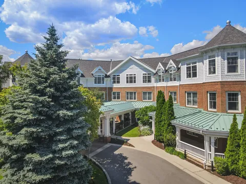 Residence with white siding, brick walls and a covered entrance drive.