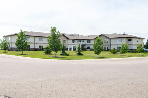 Residence building with a front driveway, lawn and young trees.