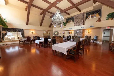 Dining room with wood flooring, tables and a high beamed ceiling.