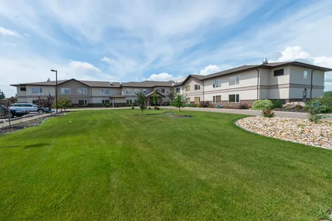 Residence facade behind a sloping lawn and landscaped beds.