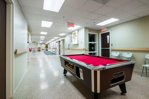 Billiard table beside a bright interior corridor.