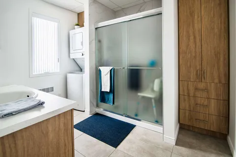 Bathroom with a vanity, shower and laundry machines.