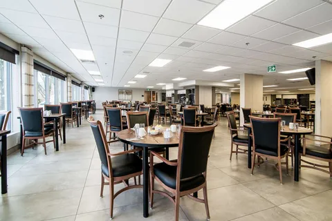 Dining room with set tables and a row of windows.