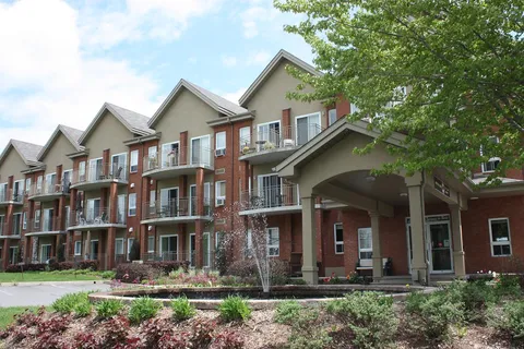 Brick residence with balconies, a covered entrance and flower beds