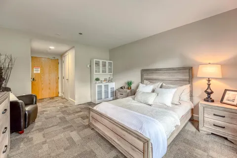 Bedroom with a white-covered bed, dresser and wooden furniture