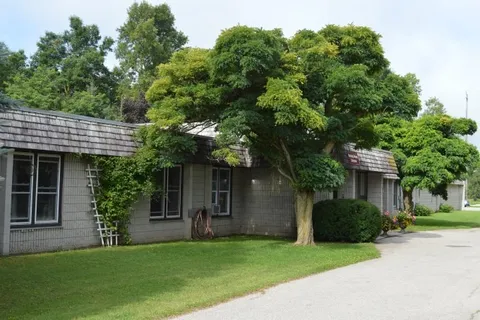 Low brick residence beside a lawn and leafy trees