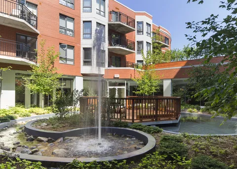 Brick residence around a courtyard with a fountain, stream and wooden bridge