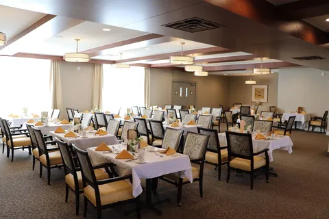 Dining room with tables set with white cloths, yellow napkins and floral centrepieces