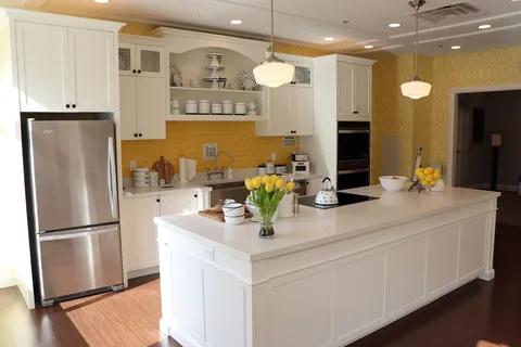 Kitchen with a white island, yellow tiled backsplash, cabinets and stainless steel refrigerator