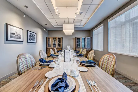 Private dining room with a long set table beneath pendant lights.