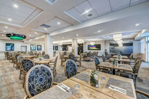 Dining room with set tables and upholstered chairs.