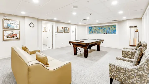 Games room with a pool table, a sofa, patterned armchairs and paintings of cars