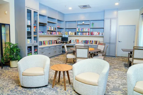 Library with blue bookshelves, upholstered chairs and a round table