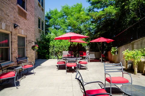 Patio with red umbrellas, cushioned chairs and tables beside the building