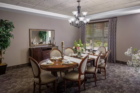 Oval dining table with place settings, a chandelier and a wall mirror