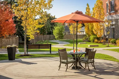 Garden patio with an orange umbrella, table, chairs and a bench