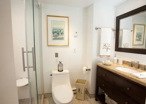 Bathroom with a glass shower, toilet and vanity beneath a large mirror