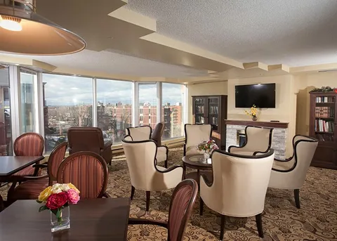 Lounge with white armchairs, windows, bookshelves and a television above a fireplace