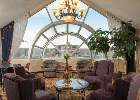Sitting room with patterned armchairs beside a large arched window