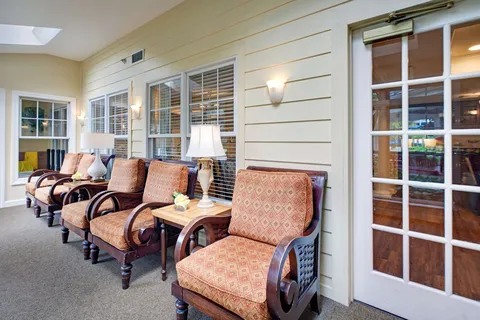 Sunroom with upholstered wicker chairs beside tall windows.