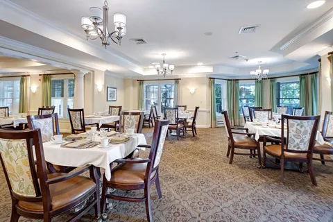 Dining room with set tables, chandeliers and windows.