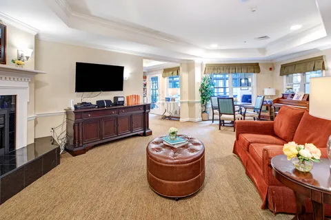 Living room with an orange sofa, television and fireplace.