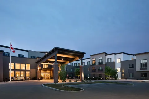 Residence building and illuminated entrance at dusk.