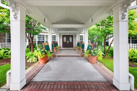 Covered entrance walkway lined with rocking chairs and flower pots