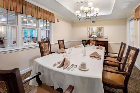 Dining room with a long set table, wooden chairs and interior windows