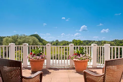 Patio with wicker chairs, flower pots and a white railing