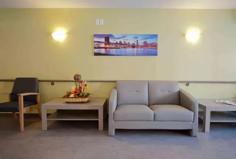 Sofa and armchair against a yellow wall with a cityscape print